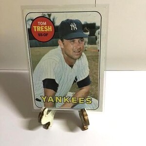 Puede incluir: Una tarjeta de béisbol con Tom Tresh de los Yankees. La tarjeta muestra una imagen en color del jugador con un uniforme a rayas y una gorra azul marino con el logotipo del equipo. La tarjeta también incluye el texto "Yankees" y "Tom Tresh SS-OF".
