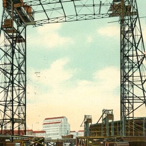 Puede incluir: Una postal antigua que representa un puente levadizo sobre una vía fluvial en Chicago, Illinois. El puente está hecho de metal y tiene una torre a cada lado. El puente está levantado, permitiendo que los barcos pasen. La postal está titulada "Lift Bridge, Halsted St. Chicago, Ill."