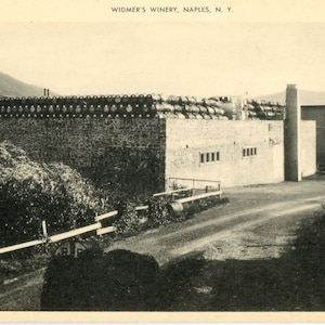 Puede incluir: Una fotografía en blanco y negro de un edificio de piedra con una fila de barriles en la parte superior. El edificio está etiquetado como "Widmer's Winery, Naples, N.Y."