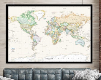 May include: A world map in a black frame hangs above a blue leather sectional sofa with a white throw blanket. The map is on a white background with green, brown, and blue details. The sofa is in a room with a brick wall and a wooden floor.