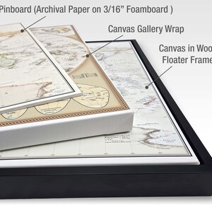 a collection of framed artworks, including a map on a foamy paper, a canvas gallery wrap, and a canvas in a wood floater frame.