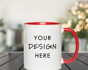 May include: White ceramic mug with a red rim and handle. The mug has the text "YOUR DESIGN HERE" printed on the front.