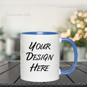 May include: White ceramic mug with a blue rim and handle. The mug has the text "YOUR DESIGN HERE" printed in black.