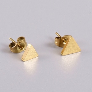 May include: A pair of gold triangle stud earrings. The earrings are made of stainless steel and have a brushed finish.