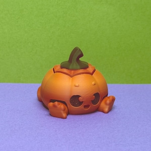 May include: A 3D-printed orange pumpkin figurine with a green stem. The pumpkin has a smiling face with two eye cutouts and small feet. The figurine is sitting on a purple surface with a green background.