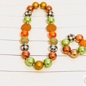 May include: A green, orange, and brown beaded necklace and bracelet set with a black and white checkered pattern.
