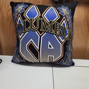 May include: Black pillow with a gold and blue graphic of the word "Columbus" with a stylized "C" and "A" in the center. The graphic is surrounded by gold and blue leaves.