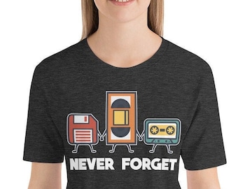 May include: A dark heather grey t-shirt with a graphic of a floppy disk, VHS tape, and cassette tape holding hands. The text "NEVER FORGET" is printed below the graphic.