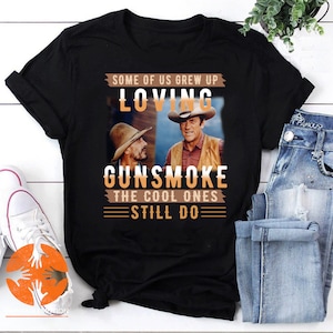 May include: Black t-shirt with a graphic of two men in cowboy hats. The text reads "Some of us grew up loving Gunsmoke. The cool ones still do."