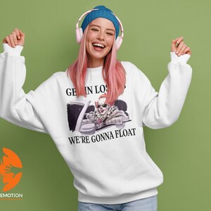 May include: White sweatshirt with a graphic of a clown driving a car. The text on the sweatshirt says "Get in Loser, We're Gonna Float."
