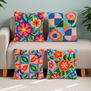Pode incluir: Quatro almofadas quadradas com desenhos florais e geométricos coloridos. As almofadas apresentam uma variedade de cores brilhantes, incluindo rosa, laranja, amarelo, azul e verde. As almofadas estão dispostas em um sofá bege.