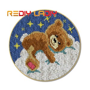 May include: A round rug with a blue background and white clouds. A brown teddy bear with a pink nose is lying on the clouds. The rug is decorated with yellow stars.