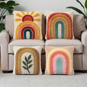 Può includere: Quattro cuscini decorativi con disegni di arcobaleni e sole. I cuscini presentano un design strutturato e trapuntato nei toni del giallo, arancione, rosso e blu. Un cuscino ha un disegno del sole e un altro ha un disegno di foglie verdi.