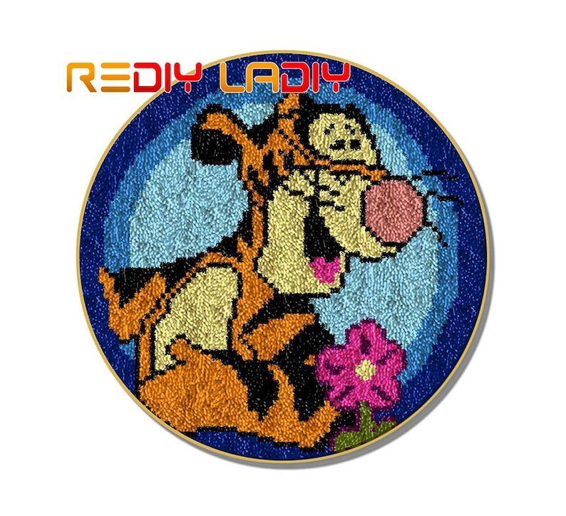 May include: A round needlepoint canvas featuring a cartoon image of Tigger from Winnie the Pooh. Tigger is orange and black with a pink nose and a flower in his paw. The background is blue with white dots.