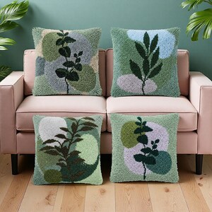 May include: Four square throw pillows with a tufted design featuring botanical patterns. The pillows have a green background with abstract shapes in shades of green, blue, and gray. Dark green plant silhouettes are centered on each pillow, creating a cohesive set.