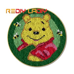 May include: A round, green, and yellow needlepoint rug with a cartoon image of Winnie the Pooh wearing a red and pink scarf. The rug is surrounded by small yellow bees.