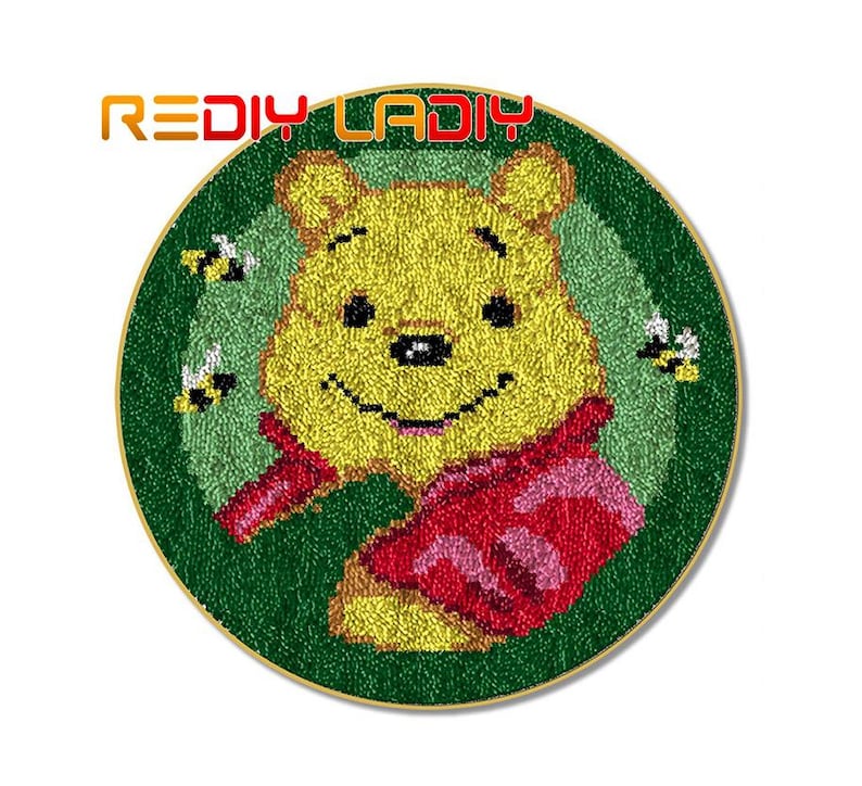 May include: A round, green, and yellow needlepoint rug with a cartoon image of Winnie the Pooh wearing a red and pink scarf. The rug is surrounded by small yellow bees.
