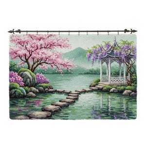 Könnte beinhalten: Ein detaillierter Wandteppich, der eine ruhige asiatische Gartenszene darstellt. Das Kunstwerk zeigt einen See mit Trittsteinen, einen weißen Pavillon mit lila Glyzinien und einen Kirschblütenbaum. Die Farbpalette umfasst Grün-, Rosa- und Blautöne.