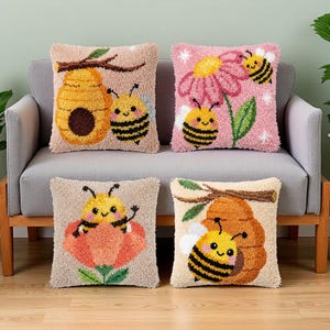 May include: Four decorative throw pillows with bee and honeycomb designs. The pillows feature a variety of colors, including tan, pink, yellow, and brown. Each pillow has a unique bee-themed design, including bees, flowers, and a beehive.