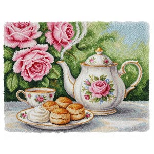 Op de afbeelding: Een tapijtbeeld van een theeparty-scène. Een witte theepot en kopje zijn versierd met roze rozen en blauwe accenten. Een bord met scones en room staat voor de theeset, met roze rozen op de achtergrond.