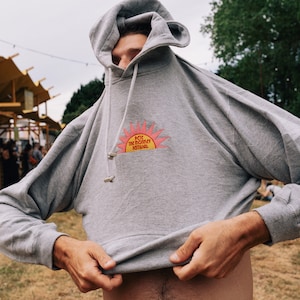 May include: A gray hooded sweatshirt with a red and yellow sun graphic and the text "Pete The Monkey Festival".