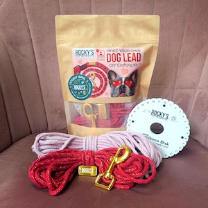 May include: A DIY dog lead crafting kit with red and pink rope, a gold-colored clasp, and a white disk for braiding. The kit includes a bag with the text "MAKE YOUR OWN DOG LEAD DIY Crafting Kit".