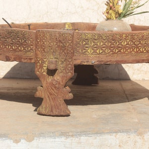 Pu&ograve; includere: Un tavolo rotondo in legno con intagli intricati e una finitura di vernice gialla. Il tavolo ha tre gambe con dettagli decorativi ed &egrave; realizzato in legno riciclato.