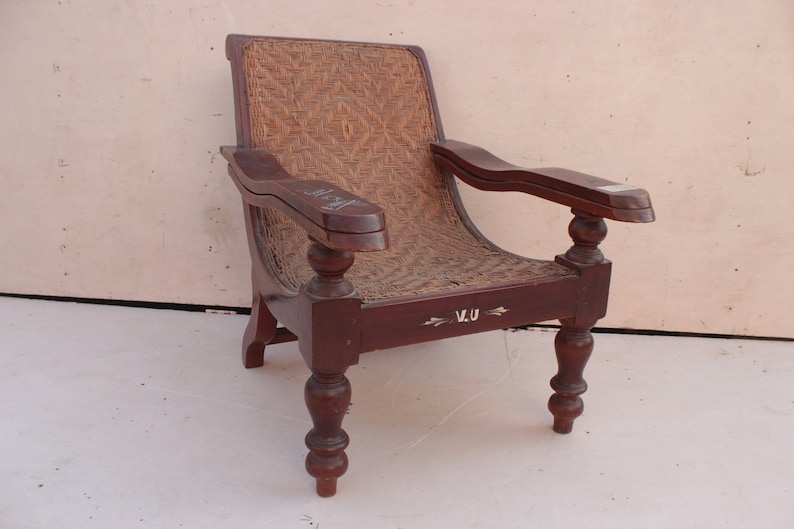 Op de afbeelding: Een donkerbruine houten fauteuil met een gevlochten rieten zitting en rugleuning. De stoel heeft gedraaide poten en armleuningen en heeft een gegraveerde inscriptie "V.U." aan de voorkant.