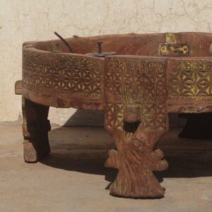 Pu&ograve; includere: Un tavolo rotondo in legno con intagli intricati e una finitura dipinta di giallo. Il tavolo ha quattro gambe intagliate in uno stile decorativo. Il tavolo &egrave; in legno scuro e ha un aspetto rustico.
