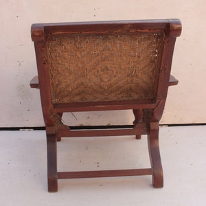 Op de afbeelding: Een houten stoel met een gevlochten rieten zitting en rugleuning. De stoel heeft een donkerbruine afwerking en een eenvoudig ontwerp.