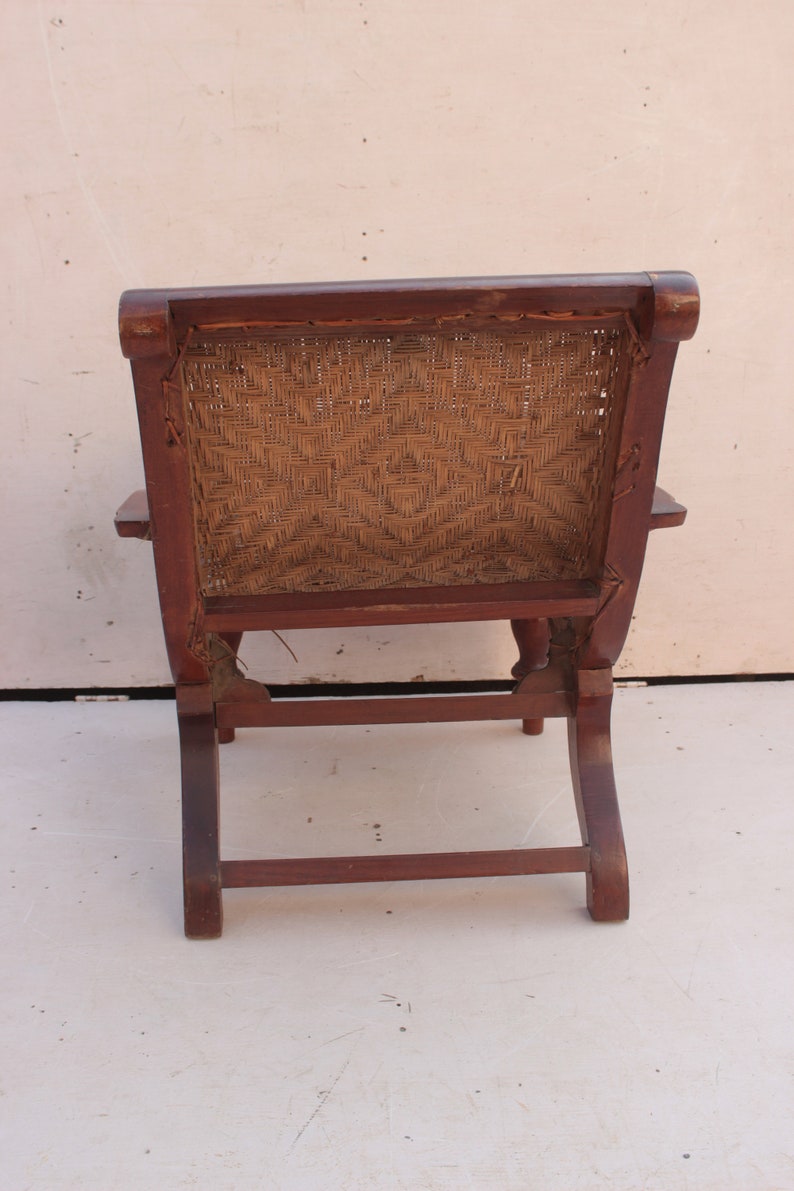 Op de afbeelding: Een houten stoel met een gevlochten rieten zitting en rugleuning. De stoel heeft een donkerbruine afwerking en een eenvoudig ontwerp.