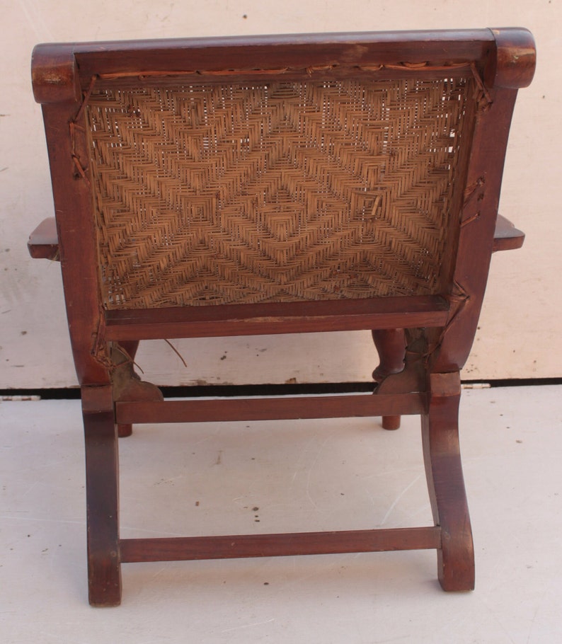 Op de afbeelding: Een houten stoel met een gevlochten rieten zitting en rugleuning. De stoel heeft een eenvoudig ontwerp met een gebogen rugleuning en vier poten.