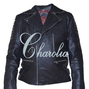 Peut inclure: Veste en cuir noir avec un motif peau de serpent texturé. Elle présente une fermeture éclair asymétrique, des revers crantés et plusieurs poches zippées. La veste a une doublure intérieure rouge et le mot "Charolia" est imprimé sur le devant.