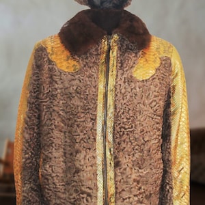 Könnte beinhalten: Eine braune Kunstfelljacke mit goldenen Schlangenleder-Applikationen und einem Reißverschluss. Die Jacke hat einen braunen Pelzkragen und eine braune Pelzmütze mit einem goldenen Band.