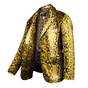 Op de afbeelding: Een gouden slangenleren blazer met een zwarte voering. De blazer heeft een klassieke snit met een revers en een knoopsluiting met twee knopen.