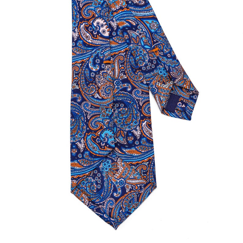 May include: A blue paisley patterned tie with orange and white accents. The tie is made of silk and has a classic design.