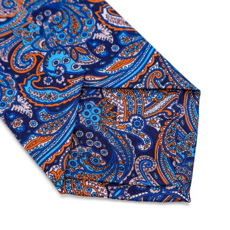 May include: A blue, orange, and white paisley patterned tie. The tie is made of a silky fabric and has a pointed tip.