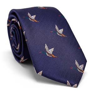 以下が含まれることがあります： ヘリンボーン柄のネイビーブルーのネクタイで、茶色、オレンジ、緑の色の飛んでいるアヒルの繰り返し模様が施されています。