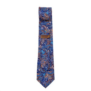 May include: A blue paisley patterned tie with orange and white accents. The tie has a label that reads "VOCATION LAND".