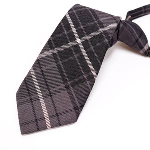 Puede incluir: Una corbata de cuadros negros y blancos con punta.