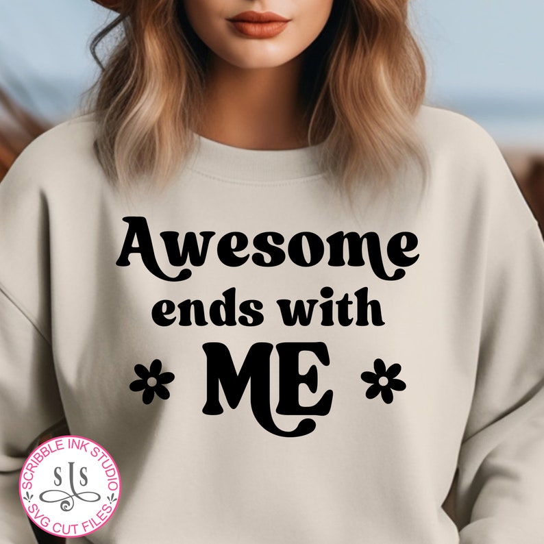 Pode incluir: Uma camisa de moletom bege com o texto "Awesome ends with *ME*" em preto, com uma flor de cada lado da palavra "ME".