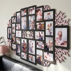 May include: A large, dark-toned multi-photo collage frame featuring a central arrangement of rectangular openings for various photographs, accented by decorative, light-colored wooden leaf and branch cutouts along the outer edges.