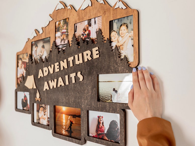 May include: A wooden photo frame shaped like a mountain range with the text "Adventure Awaits" in the center. The frame has eight openings for photos, each with a white border. The frame is brown with a dark wood stain.