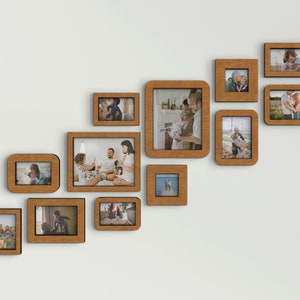 K&ouml;nnte beinhalten: Eine Anordnung von Holzbilderrahmen in verschiedenen Gr&ouml;&szlig;en an einer wei&szlig;en Wand. Die Rahmen enthalten Fotos und bilden eine Galeriewand. Die Rahmen haben eine warme, nat&uuml;rliche Holzoberfl&auml;che.