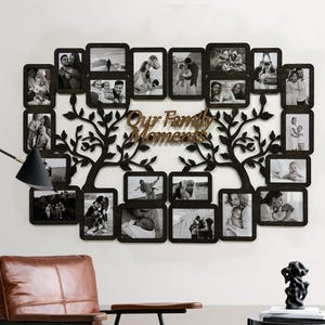 Puede incluir: Marco de fotos de madera negro con un diseño de árbol y múltiples aberturas para fotos. El marco tiene las palabras "Our Family Moments" en letras marrones.