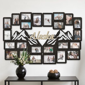 May include: A wooden photo frame with a mountain design and the word "Alaska" in the center. The frame holds 20 photos of a family, including photos of them skiing and enjoying the outdoors.