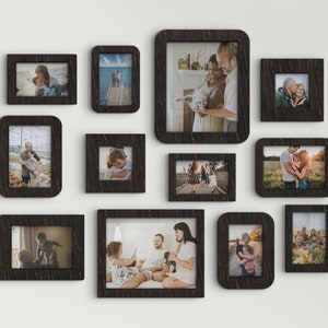 May include: A wall gallery of black picture frames with various family photos. The frames are arranged in a staggered pattern and feature photos of people of different ages and ethnicities.