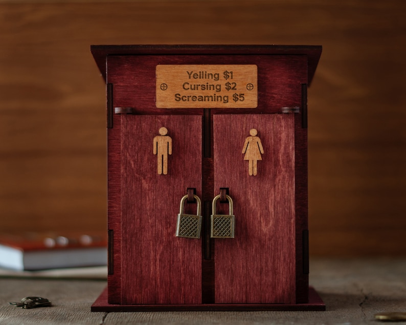 May include: A wooden box with two doors, each with a lock and a small figure of a person. The box has a sign that reads "Yelling &pound;1, Cursing &pound;2, Screaming &pound;5".