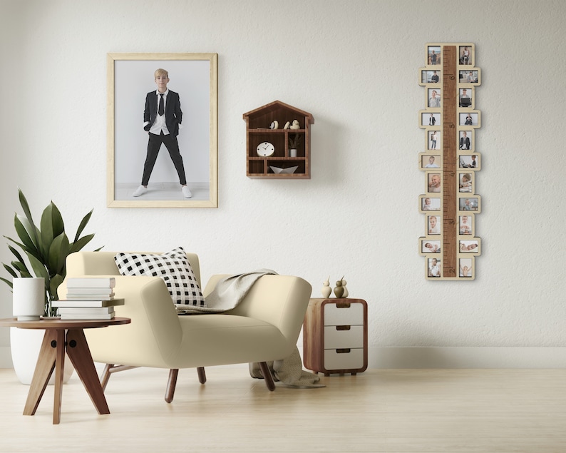 May include: A wooden photo frame with a ruler on the side and multiple slots for pictures. The frame is hanging on a white wall above a beige armchair with a black and white checkered pillow. There is a small wooden shelf with a birdhouse design on the wall above the armchair.
