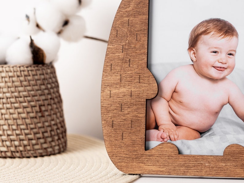 Puede incluir: Un marco de fotos de madera con forma de oso con un recorte para una foto. El marco es marr&oacute;n y tiene un acabado de madera natural. Una foto de un beb&eacute; est&aacute; en el marco.